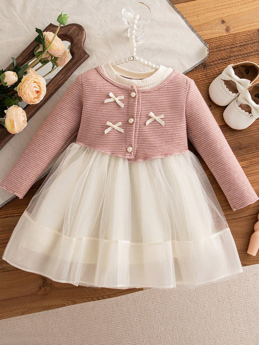 Vestido rosa y marfil para bebé con lazos decorativos y falda de tul, vista frontal.