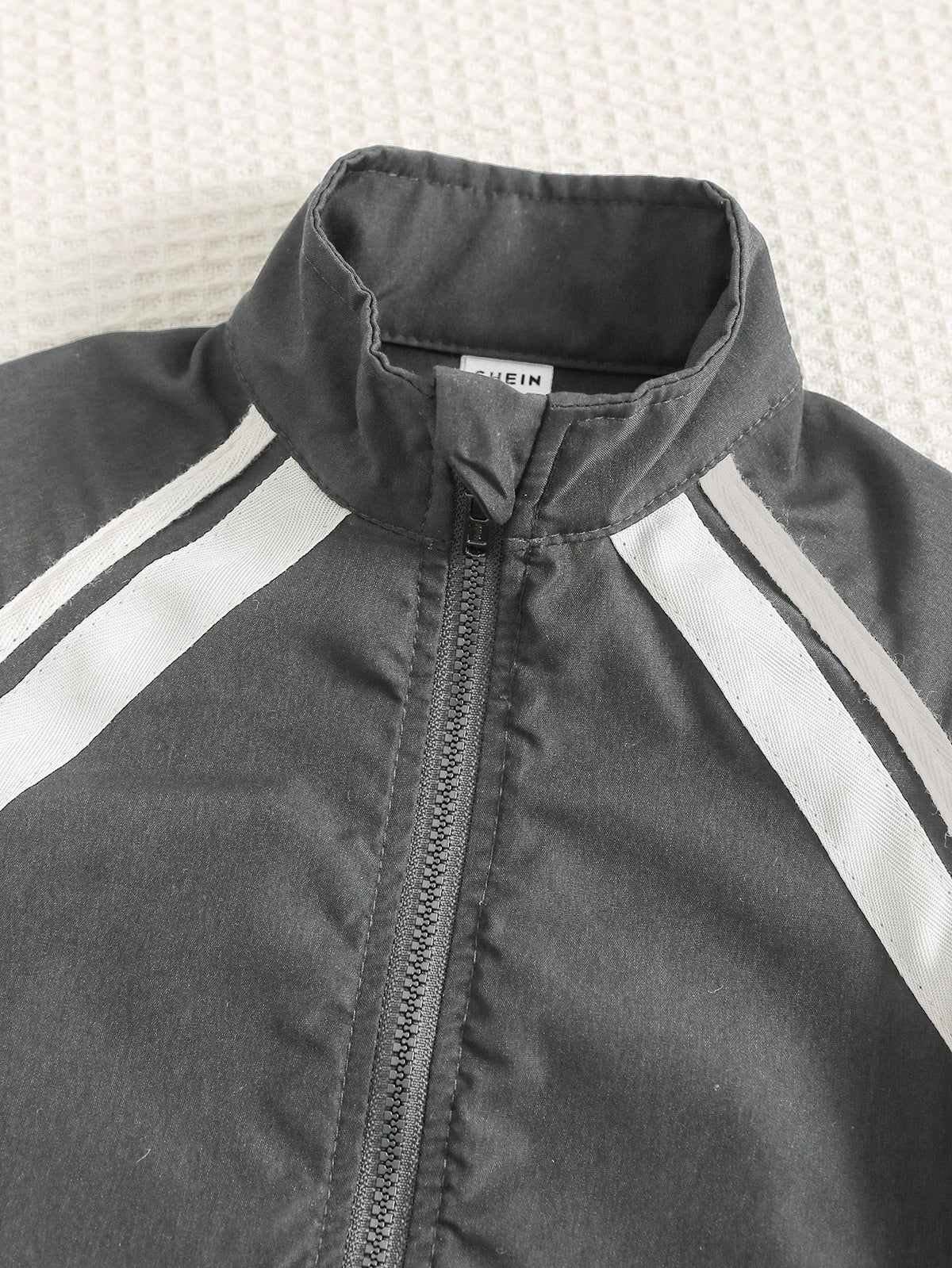 Prenda gris chaqueta deportiva para bebe con cuello alto y cremallera
