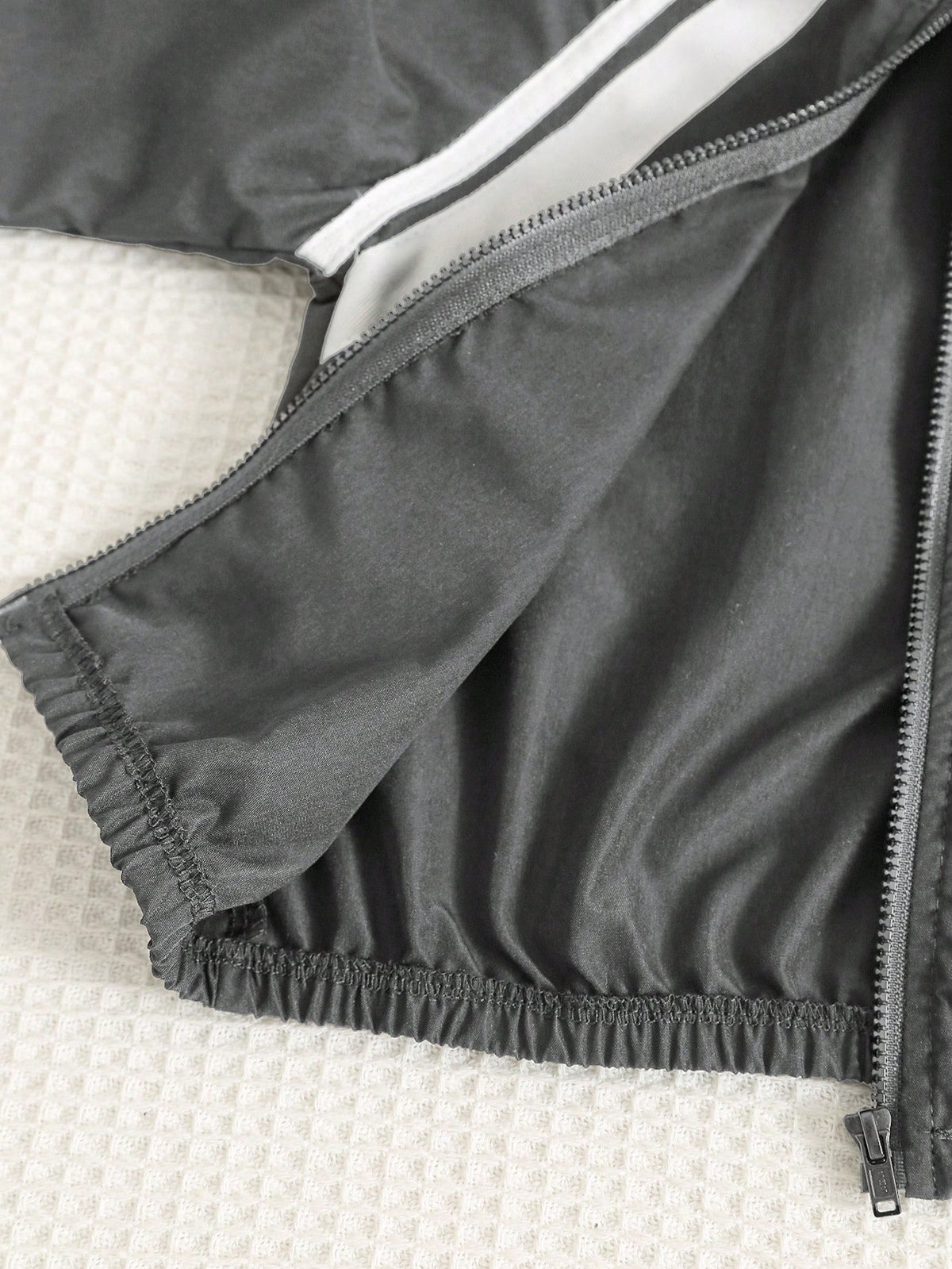 Prenda gris chaqueta deportiva para bebe con detalle de cremallera y elástico