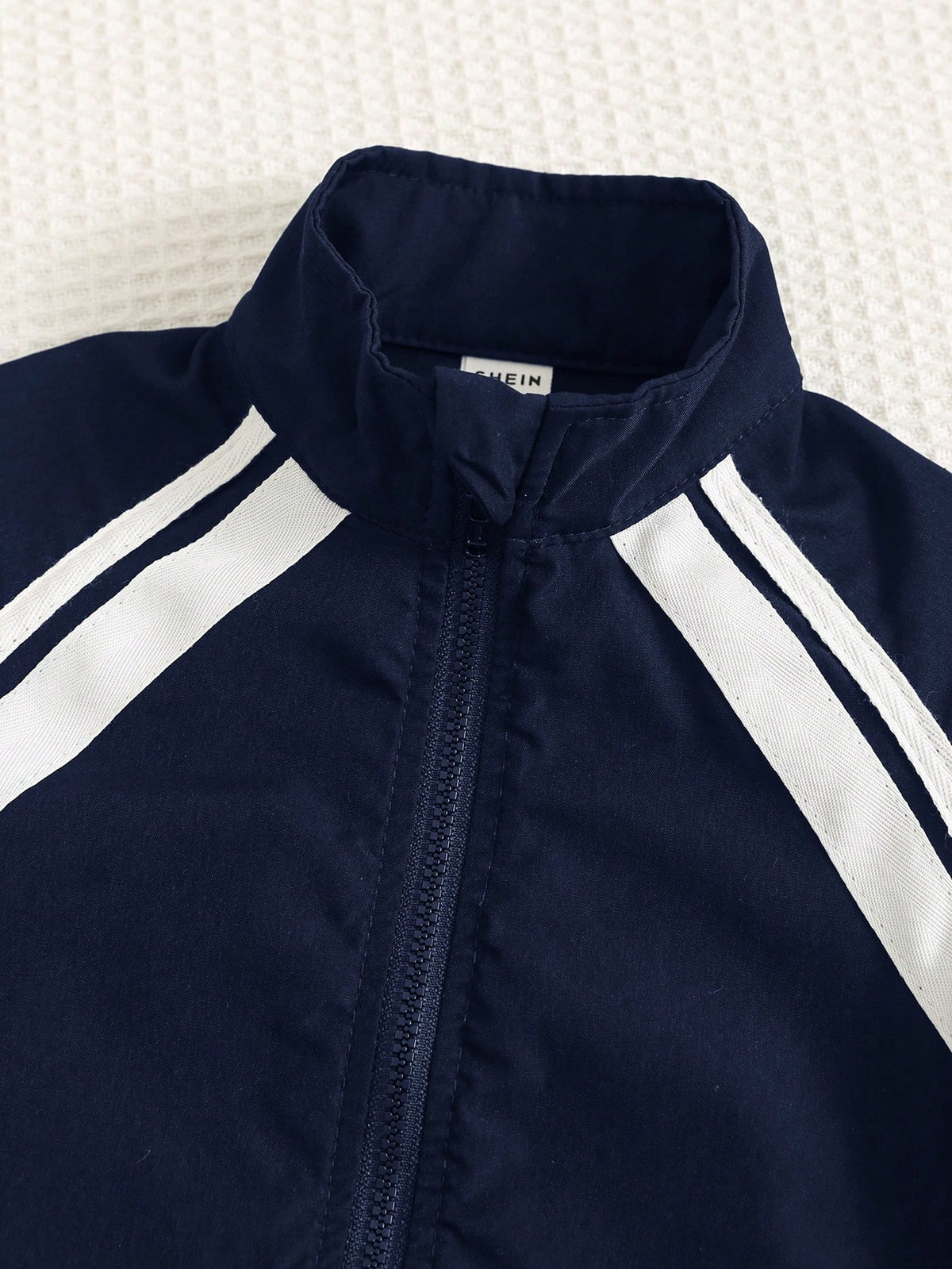 Prenda azul chaqueta deportiva para bebe con cuello alto y cremallera