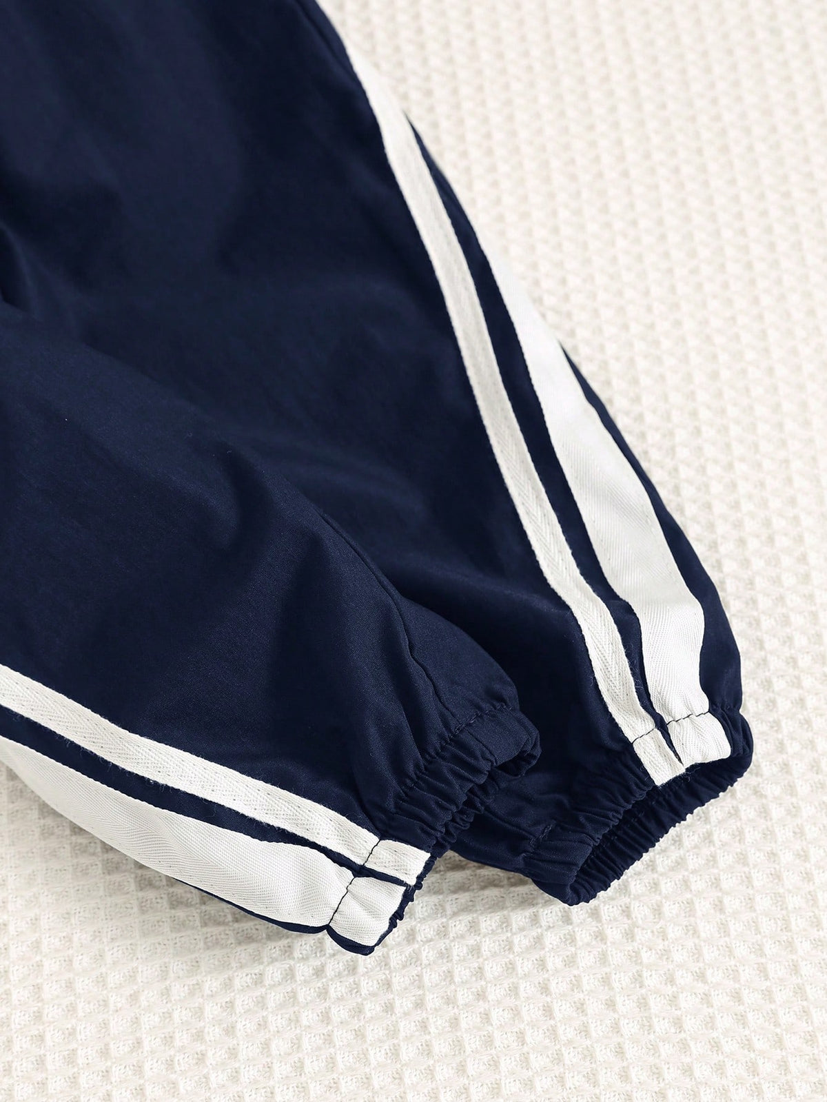 Prenda azul chaqueta deportiva para bebe con detalle de cremallera y elástico