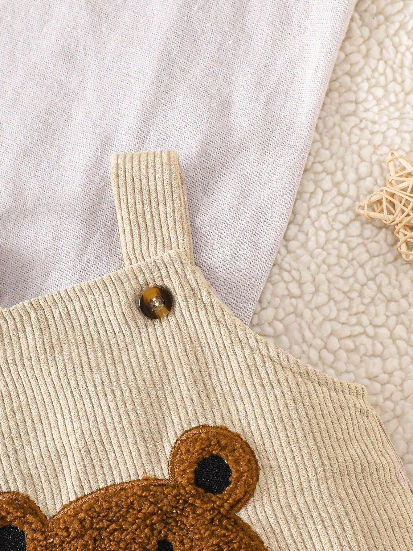 Prenda beige peto para bebe con detalle de tirantes y botones decorativos