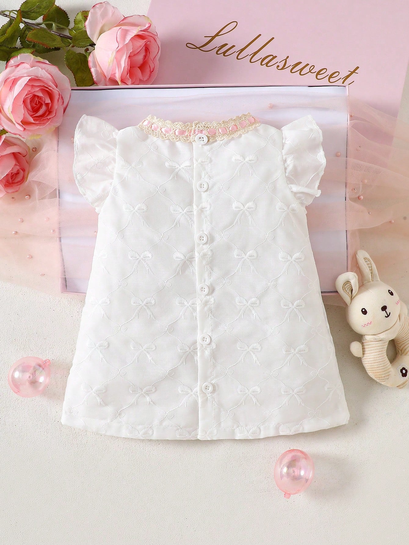 Prenda blanca vestido para bebe con encaje rosa y lazo vista trasera