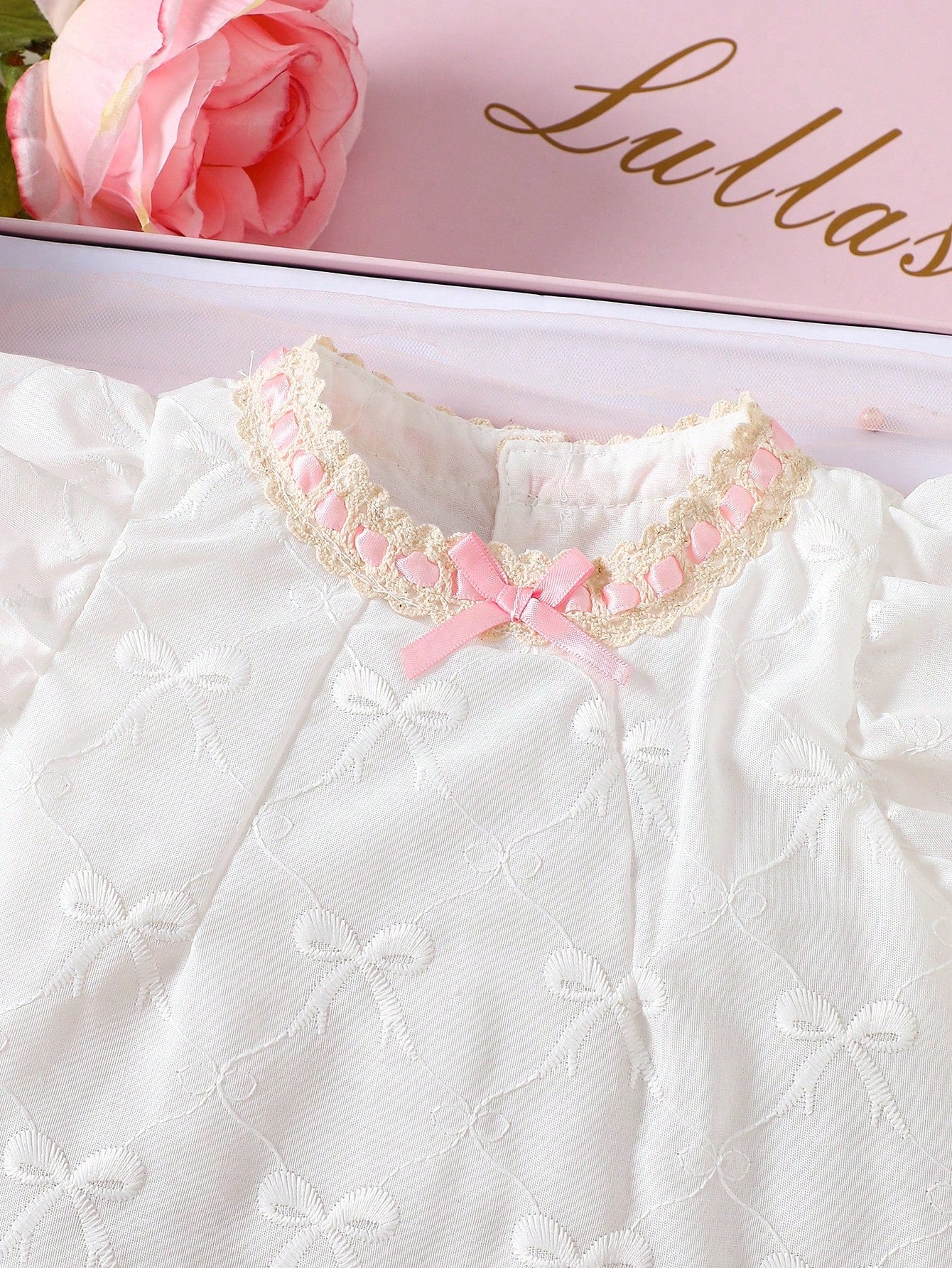 Prenda blanca vestido para bebe con detalle de cuello bordado y lazo rosa