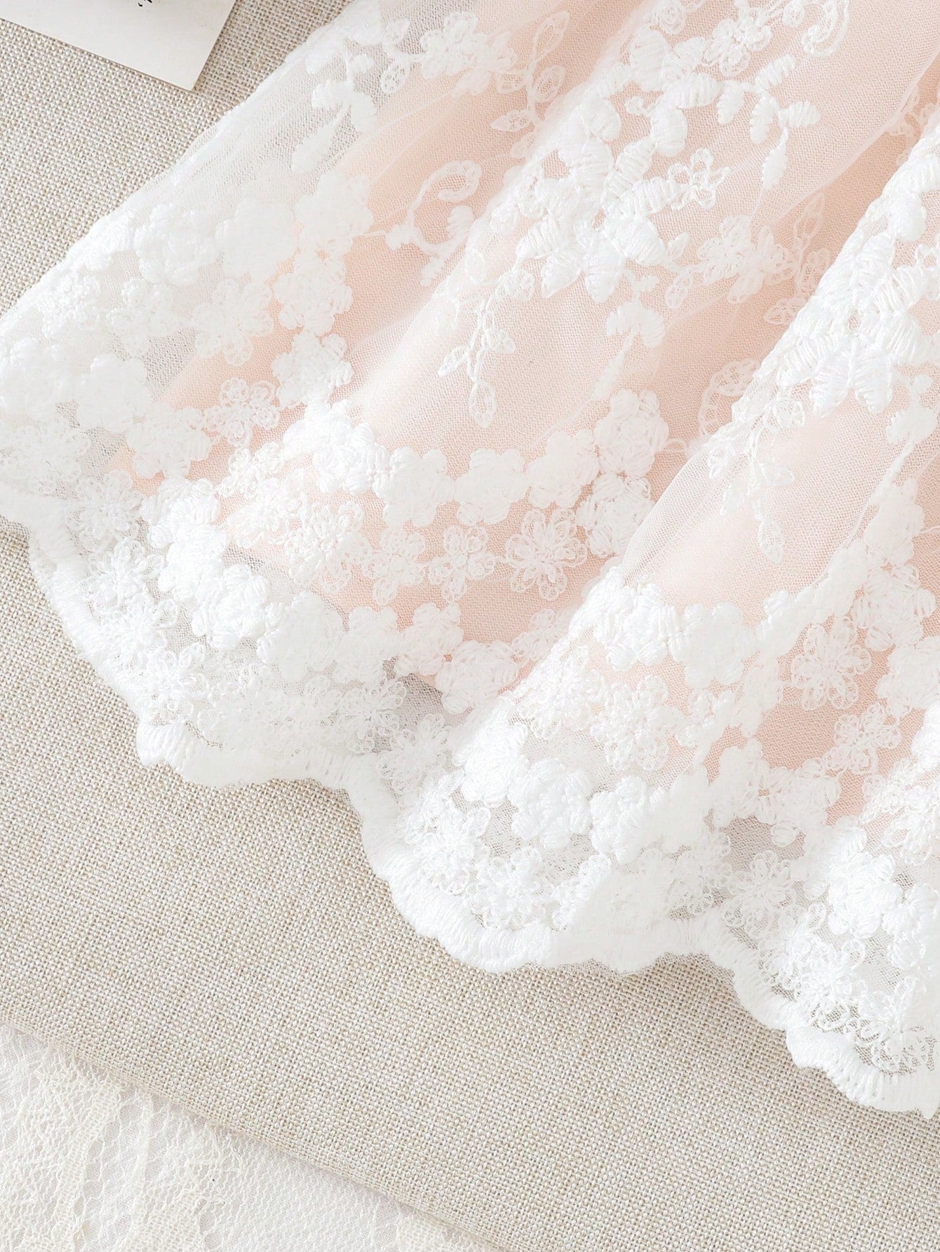 Prenda rosa claro vestido para bebe con detalle de falda bordada y acabado ondulado