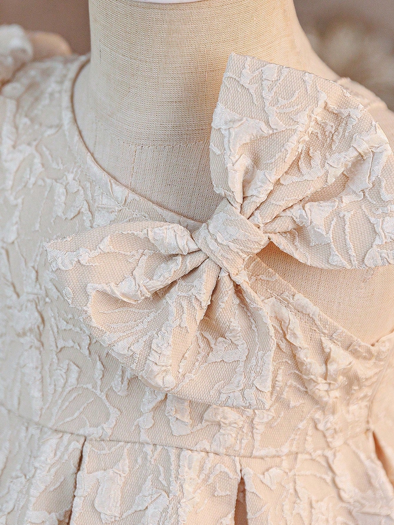 Prenda champán vestido para bebe con detalle de lazo decorativo en hombro