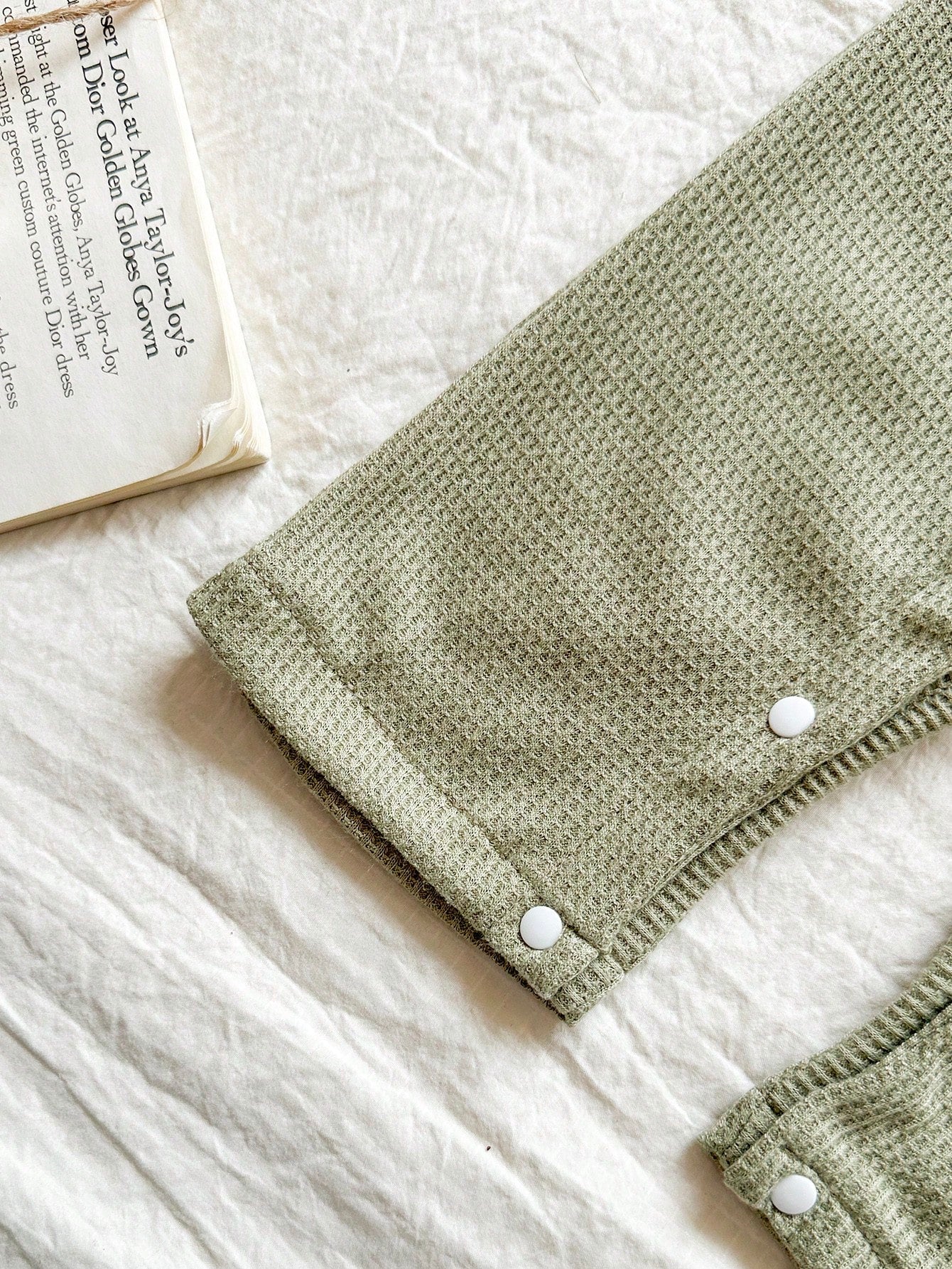 Prenda verde conjunto para bebe con broches inferiores y acabado texturizado detalle de pierna