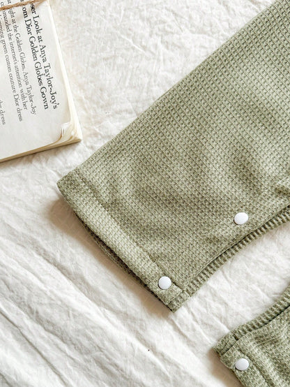 Prenda verde conjunto para bebe con broches inferiores y acabado texturizado detalle de pierna