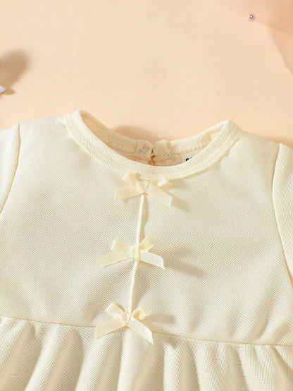 Prenda beige vestido para bebe detalle lazos frontales
