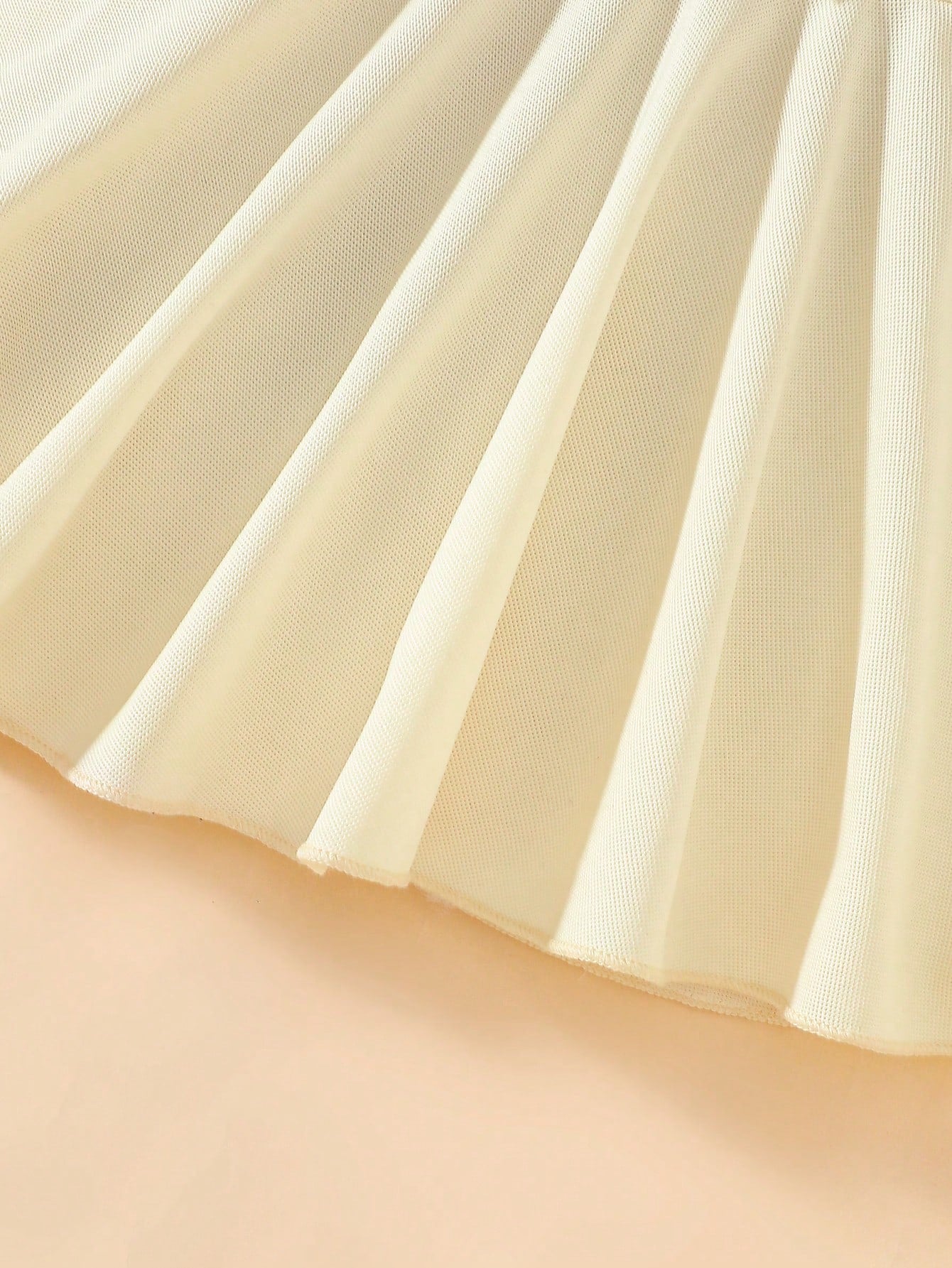 Prenda beige vestido para bebe detalle falda acampanada