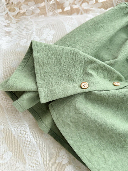 Prenda verde vestido para bebe detalle de botones delanteros y acabado