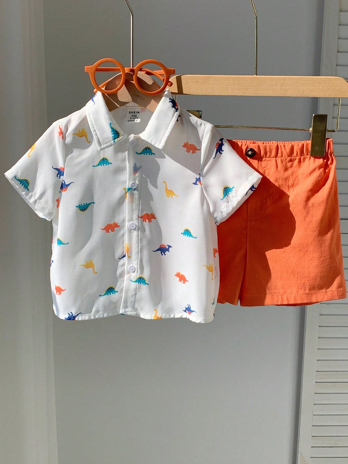 Prenda blanca conjunto para bebe con dinosaurios y short naranja vista frontal
