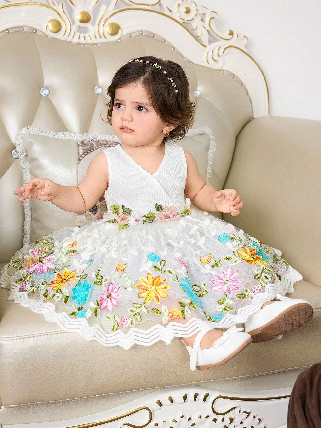 Prenda blanca vestido para bebe con falda de malla floral en posición sentada