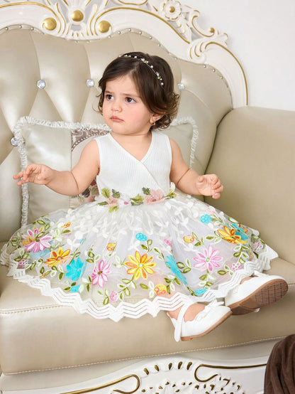 Prenda blanca vestido para bebe con falda de malla floral en posición sentada