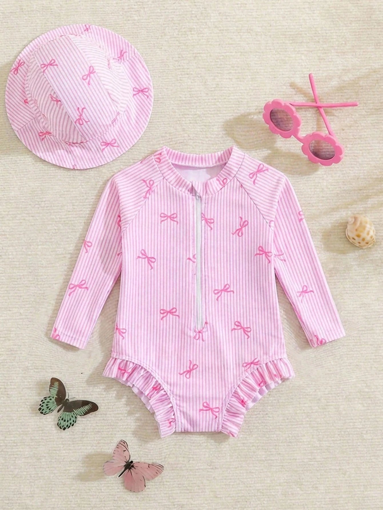 Prenda rosa traje de baño para bebe con rayas y lazos vista frontal con gorro
