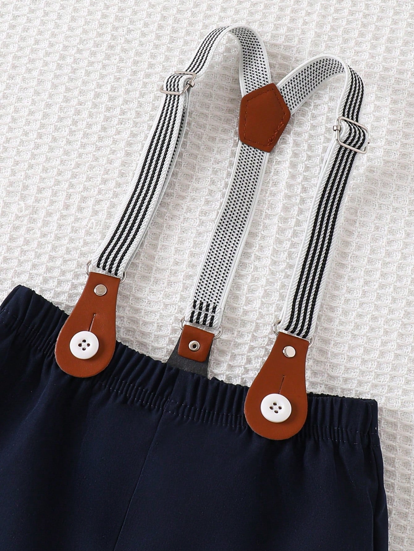 Prenda azul pantalón corto para bebe con tirantes detalle de ajuste