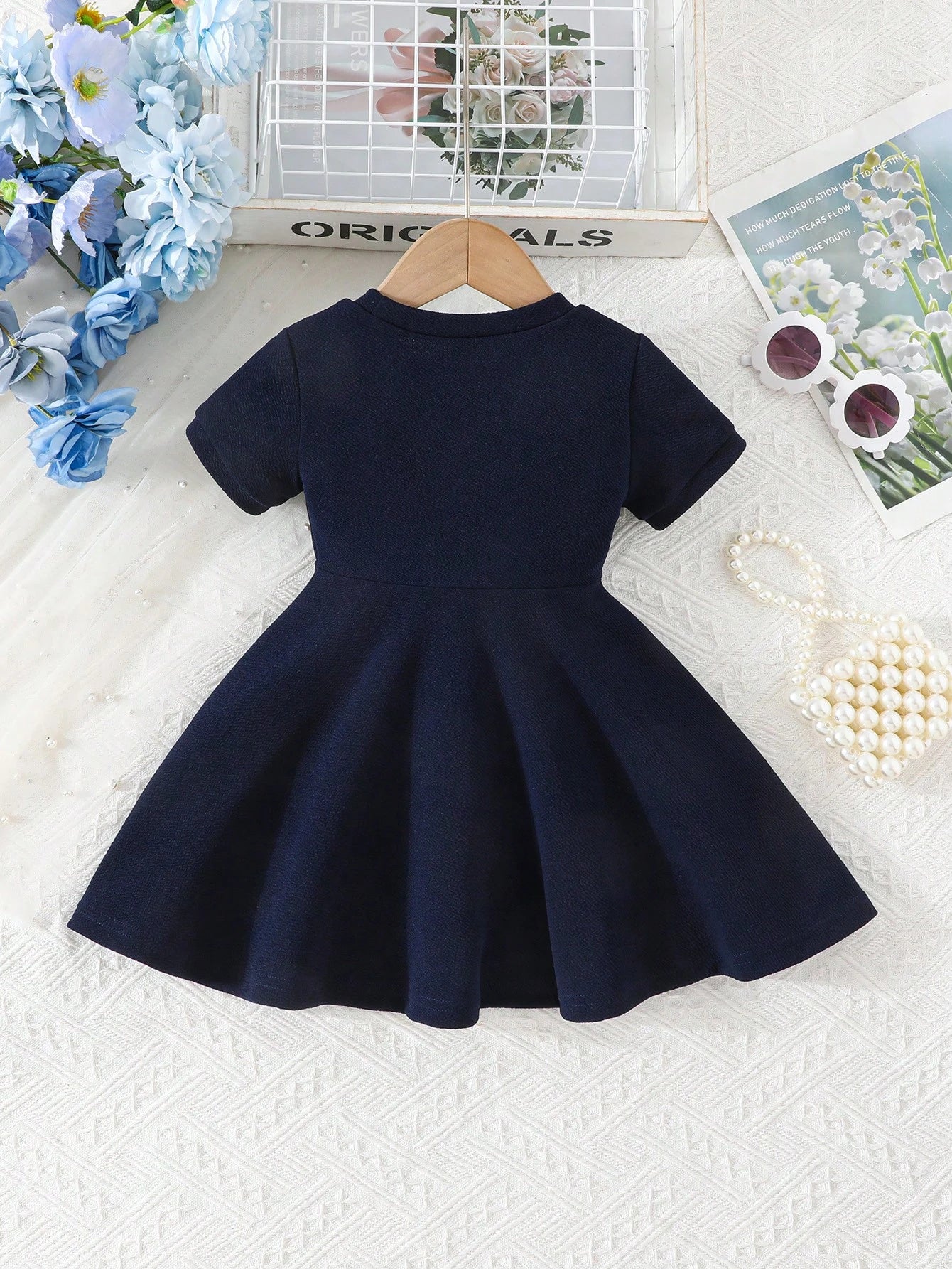 Prenda azul marino vestido para bebe con lazo blanco vista trasera

