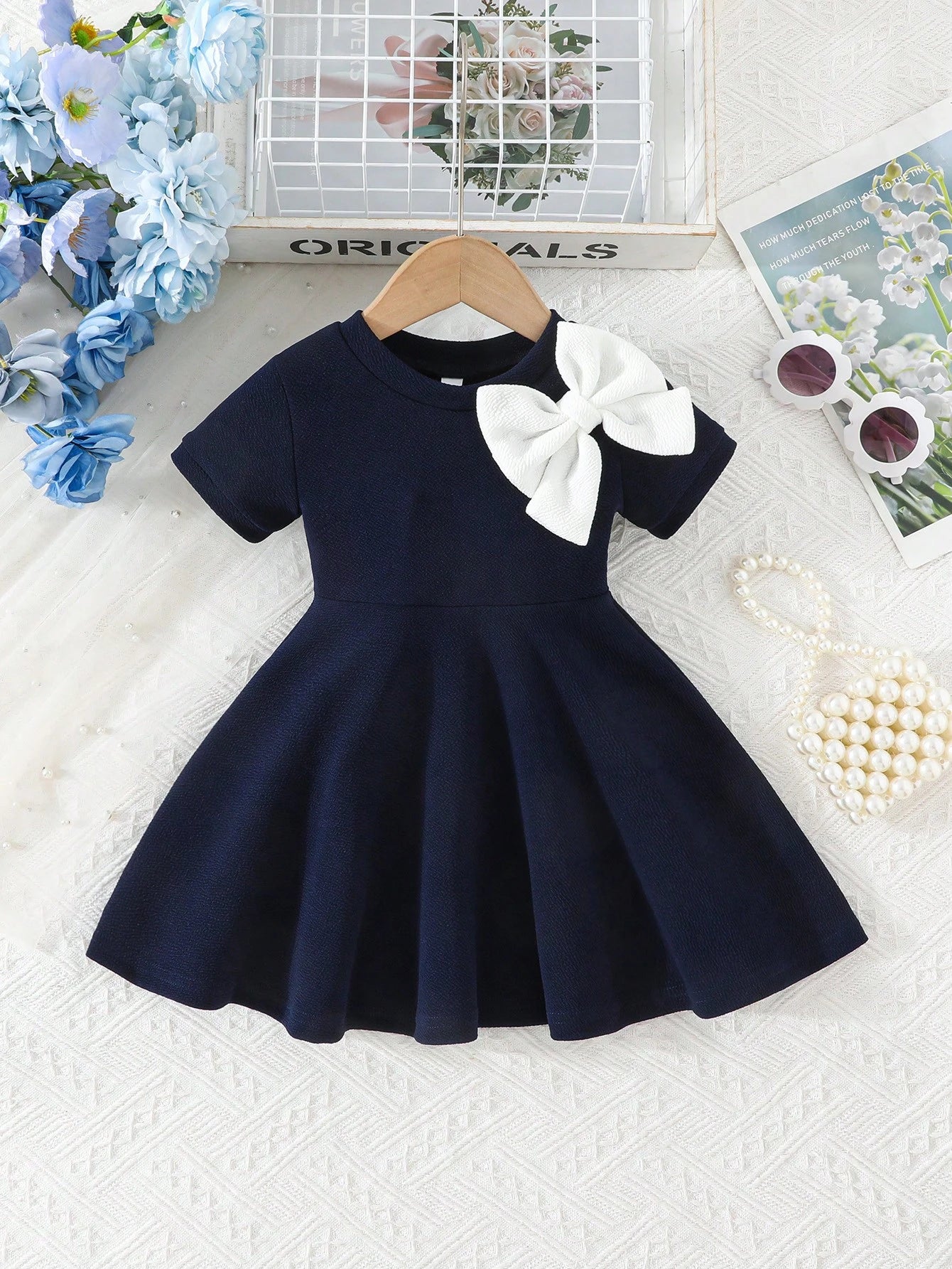Prenda azul marino vestido para bebe con lazo blanco vista frontal
