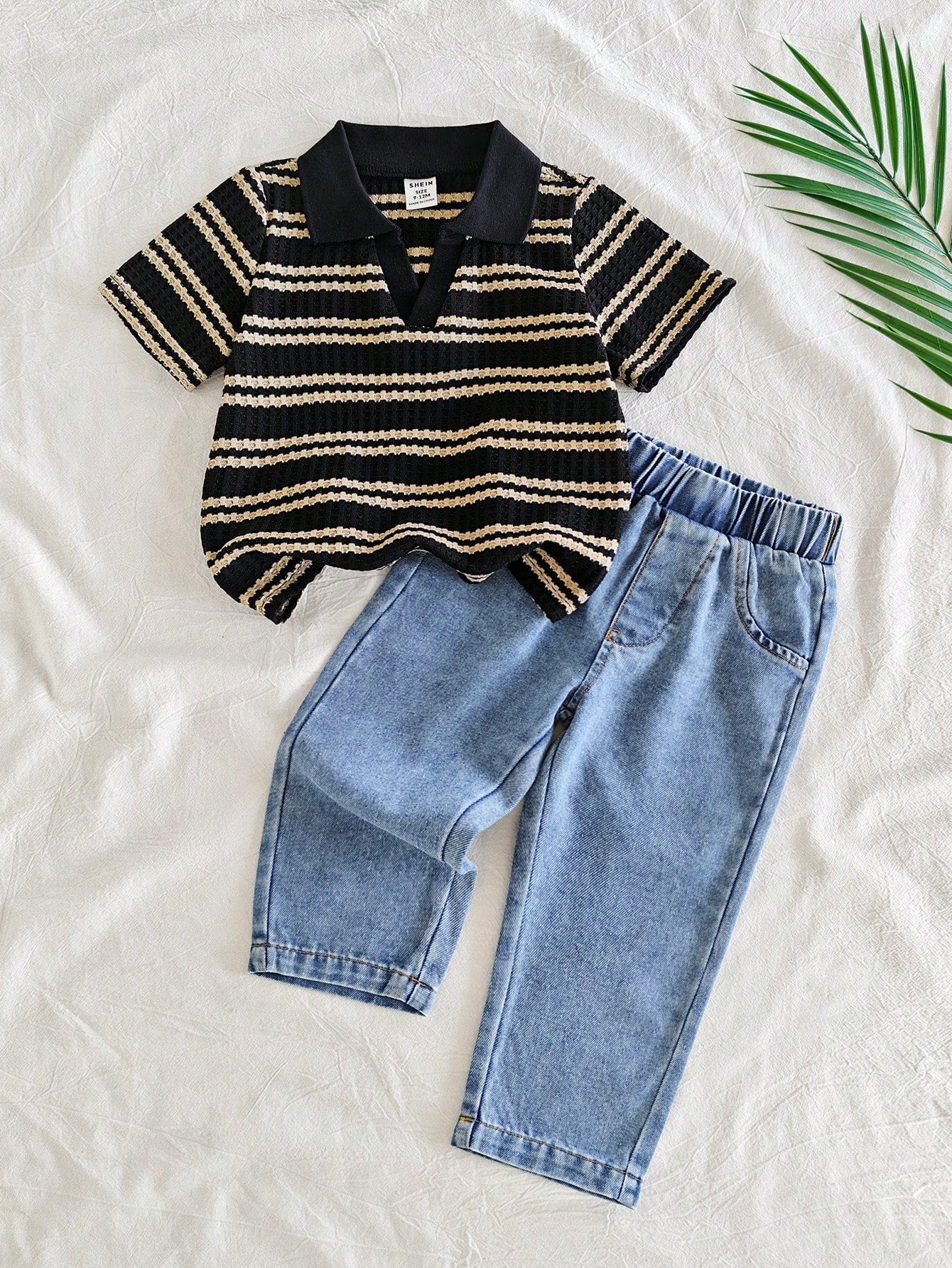 Prenda negra conjunto para bebe con camiseta tipo polo y pantalón de mezclilla vista frontal

