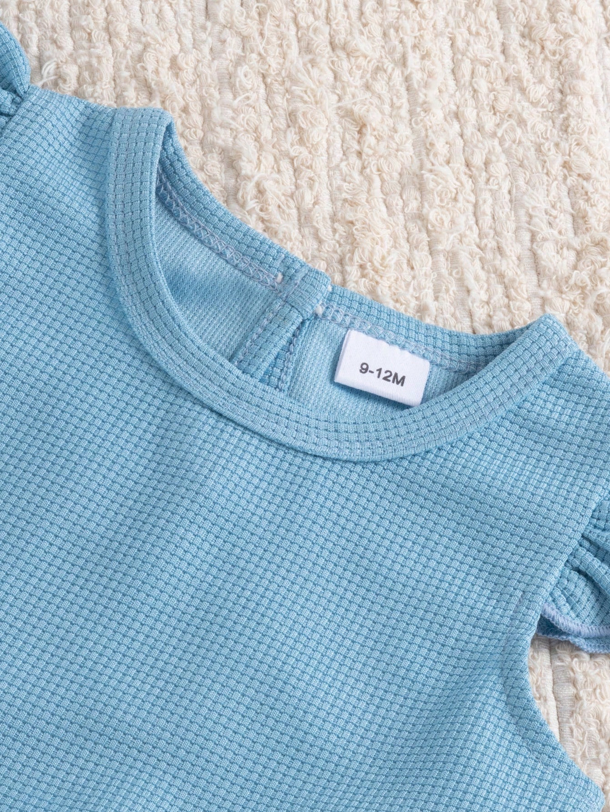 Blusa celeste para bebé con detalle de cuello redondo y tejido de textura tipo gofre.