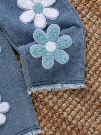 Pantalón de mezclilla azul para bebé con flores blancas y celestes en relieve y ruedos deshilachados.