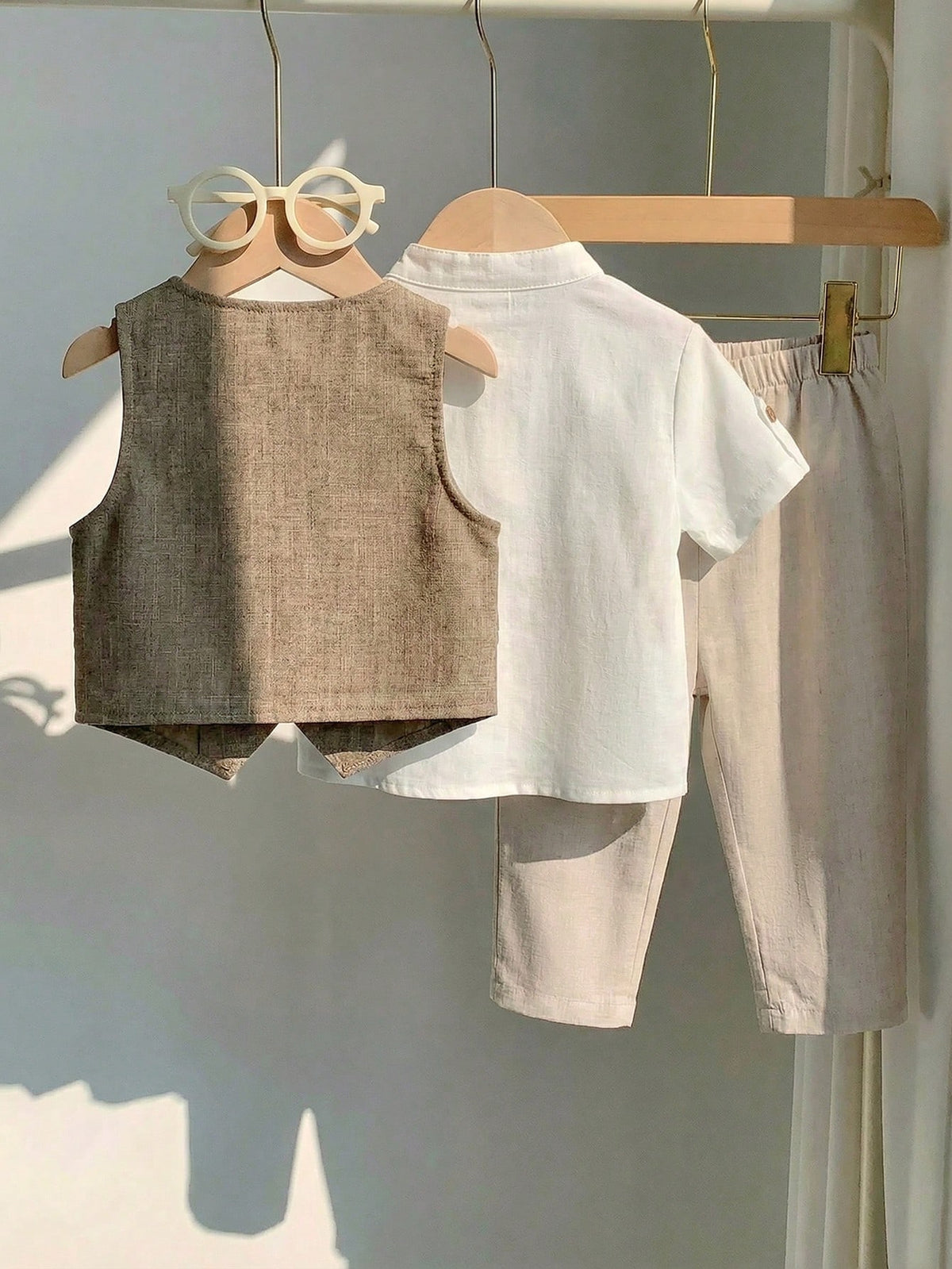Conjunto beige para bebé con chaleco de espalda lisa, camisa blanca y pantalón largo, vista trasera