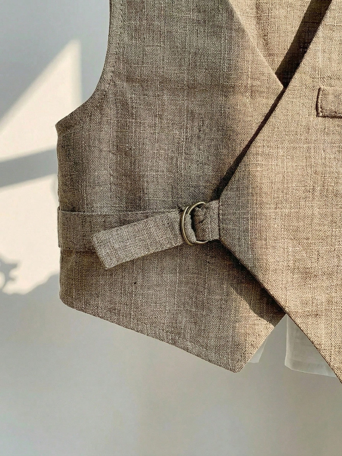 Conjunto beige para bebé con detalle de chaleco cruzado y correa lateral con hebilla metálica