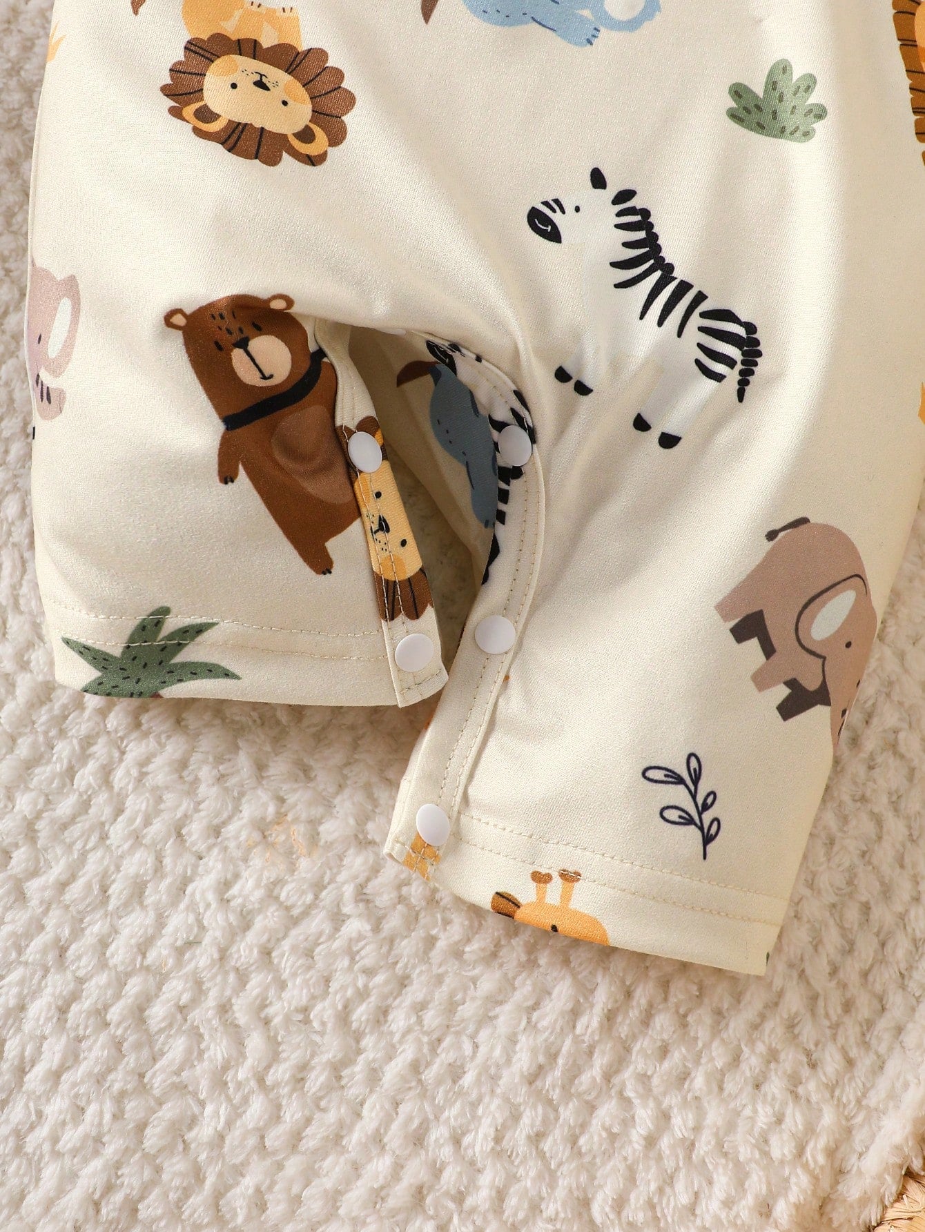 Prenda crema conjunto safari para bebe con detalle de botones inferiores y estampado animal