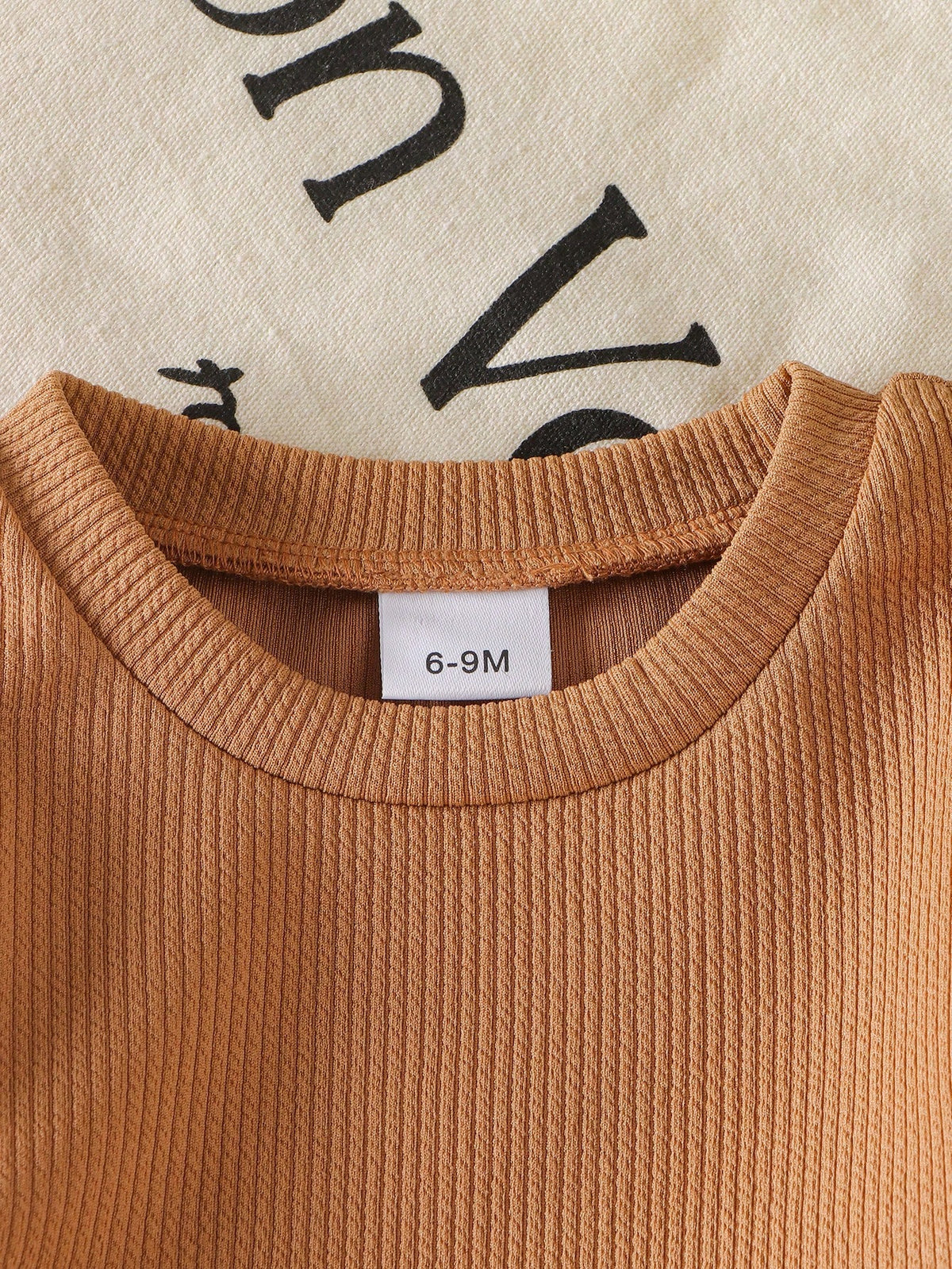Camiseta caqui para bebé con detalle de cuello redondo y tejido acanalado.