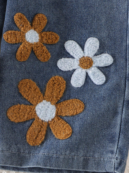 Pantalón azul de mezclilla para bebé con flores blancas y cafés en relieve, detalle de aplicaciones florales.