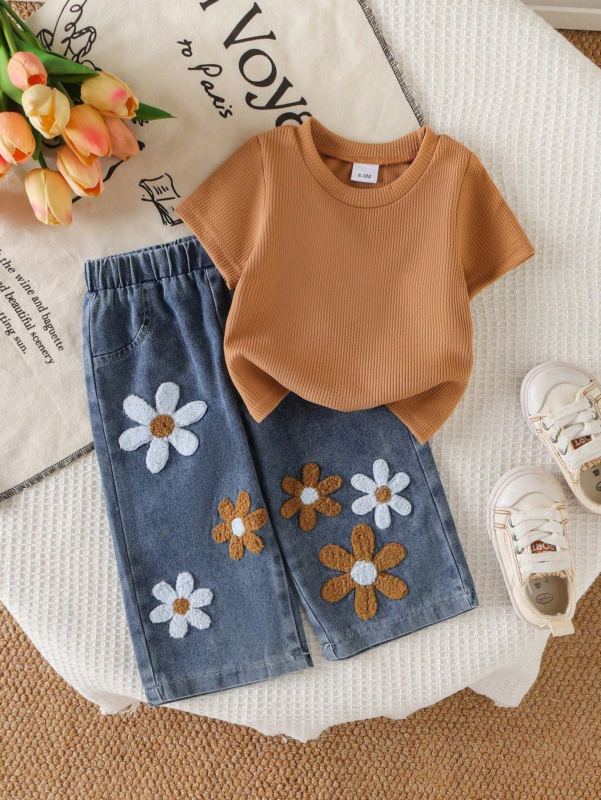 Conjunto caqui para bebé con camiseta acanalada y pantalón de mezclilla azul con flores en relieve, vista frontal.
