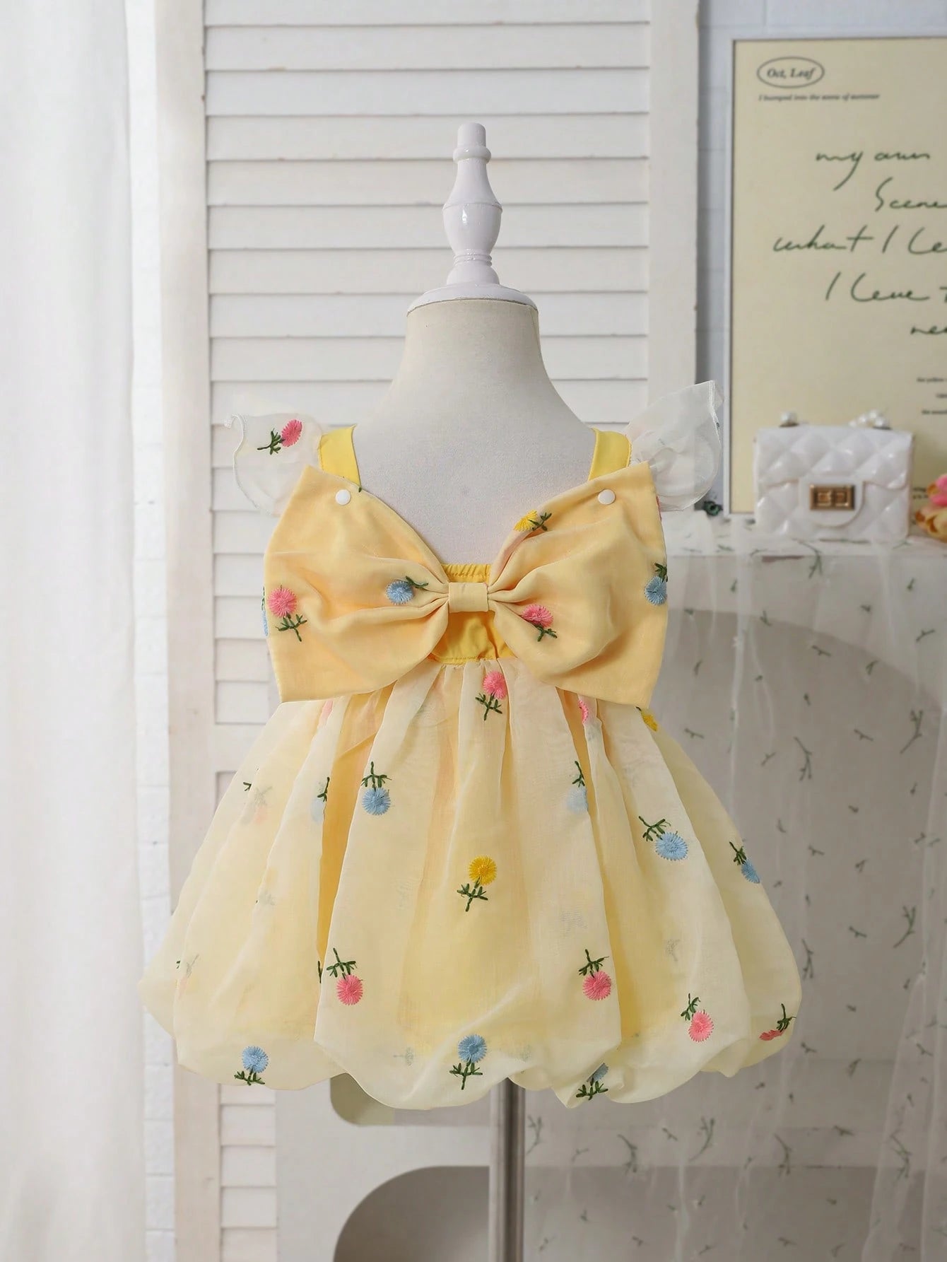 Prenda amarilla vestido para bebe con lazo grande en espalda vista posterior