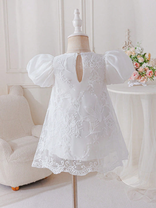 Prenda blanca vestido para bebe, vista posterior en maniquí con detalle de abertura trasera
