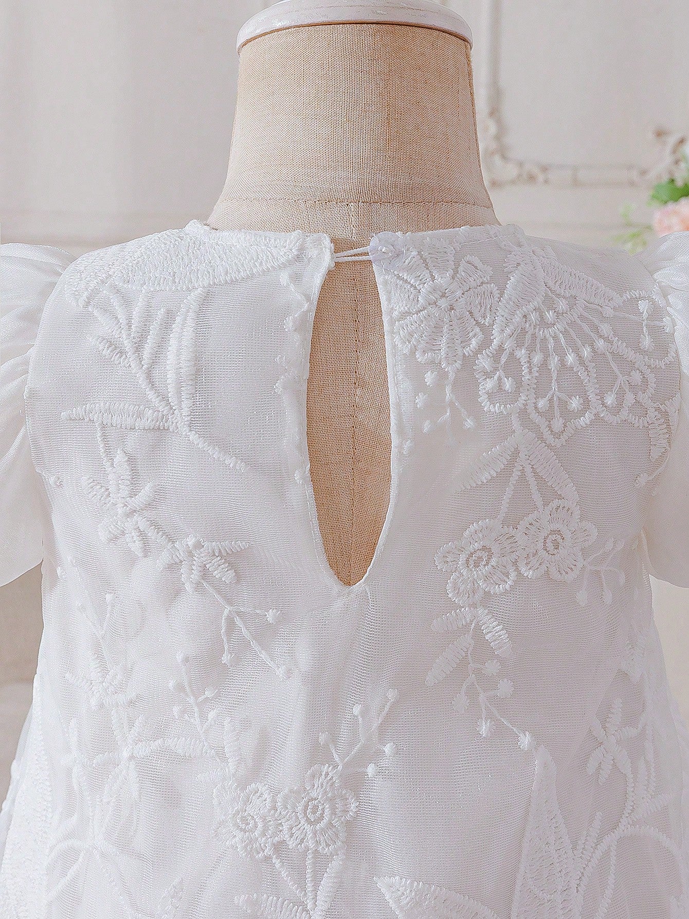 Prenda blanca vestido para bebe, detalle del bordado y cierre trasero
