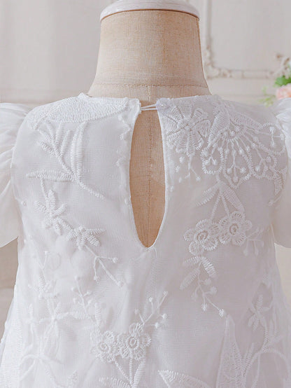 Prenda blanca vestido para bebe, detalle del bordado y cierre trasero
