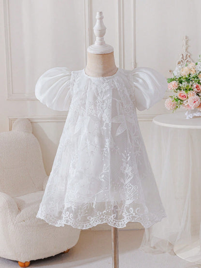 Prenda blanca vestido para bebe, vista frontal en maniquí con manga abullonada
