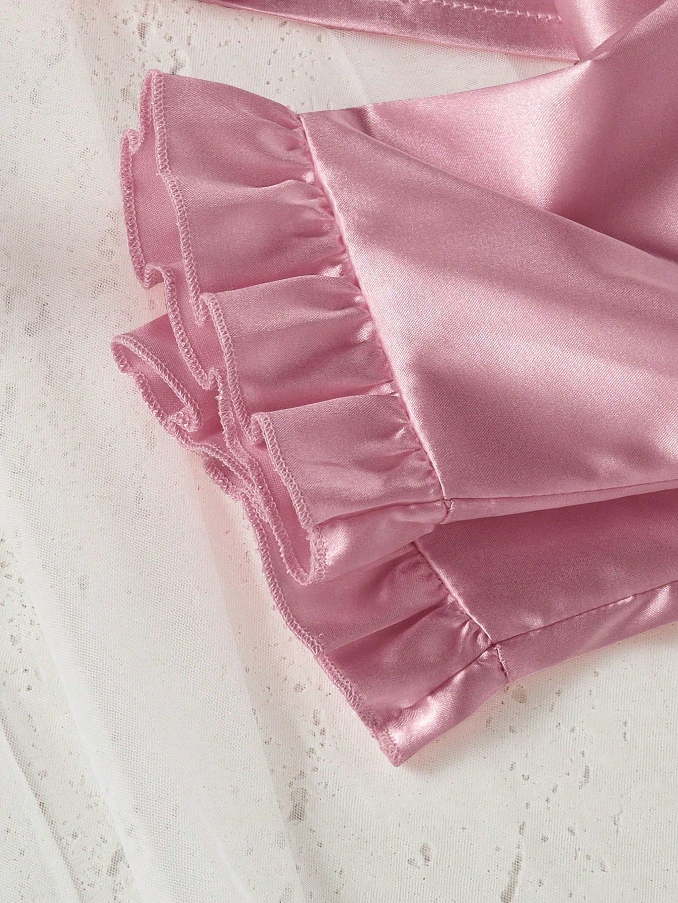 Prenda rosa pijama de satén para bebe con detalle de volantes en el pantalón