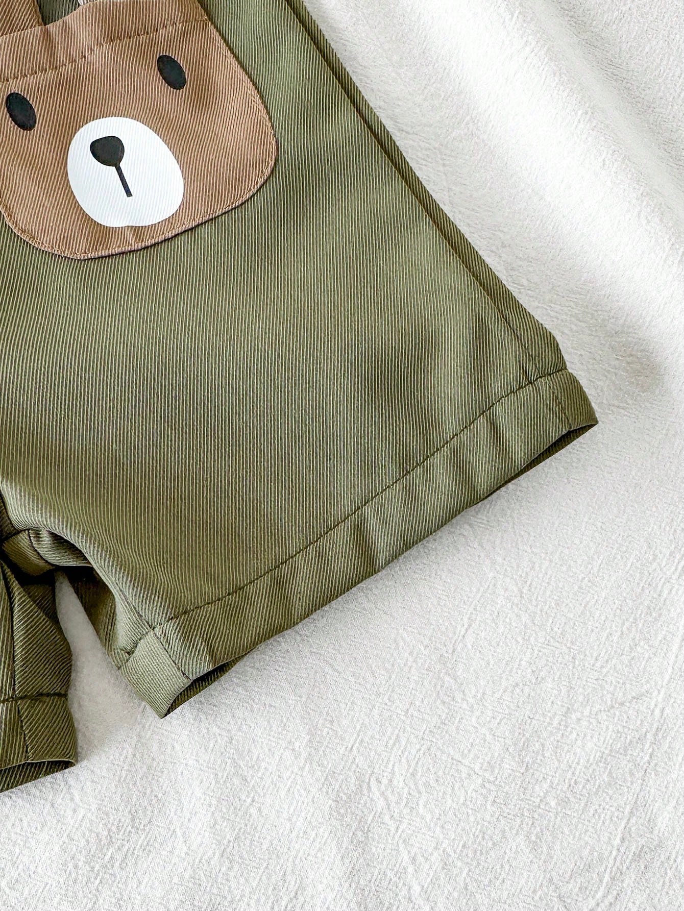 Prenda verde overol para bebe detalle de bolsillo con diseño de osito