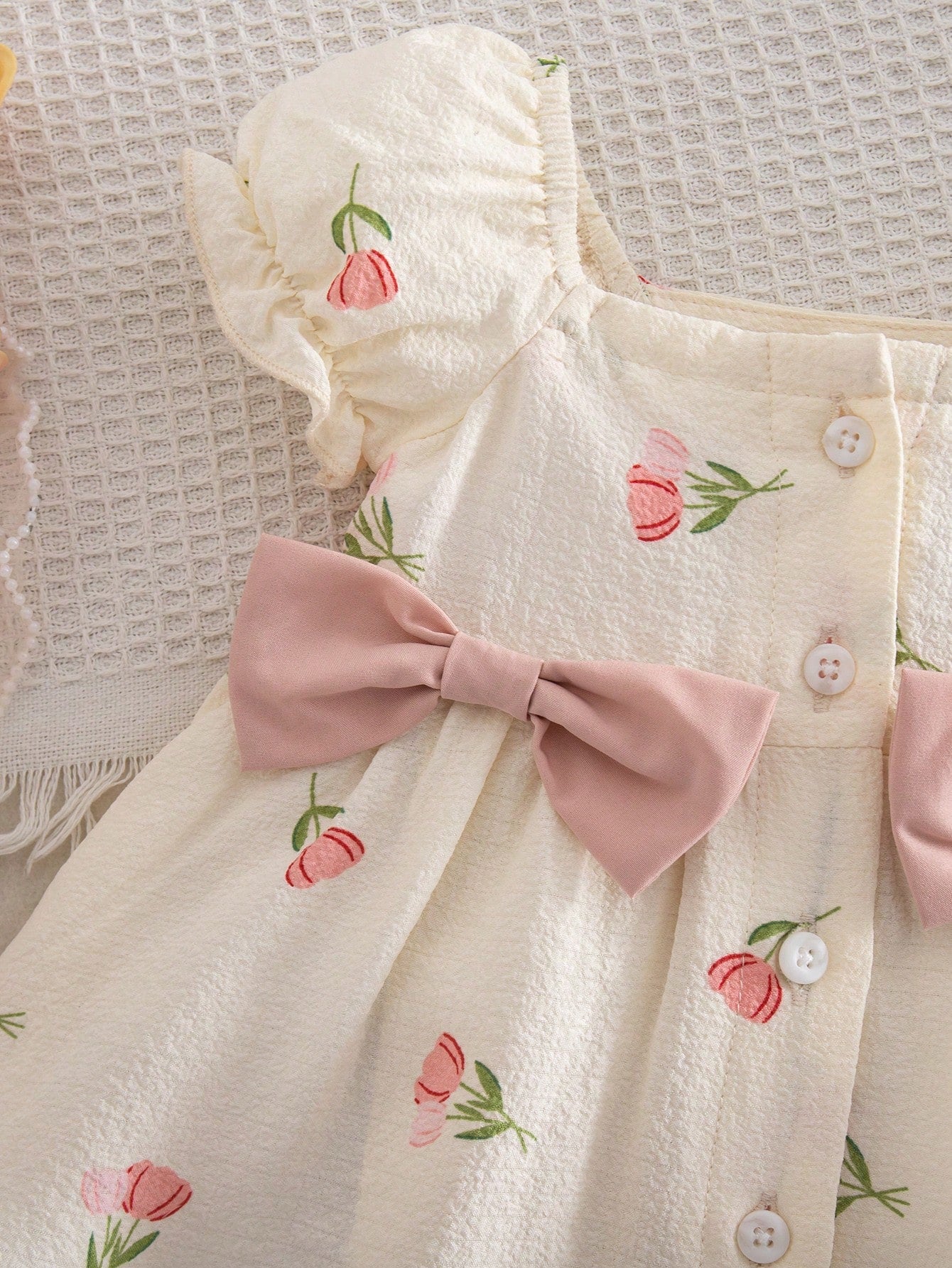 Prenda crema vestido para bebe detalle de botones y lazo rosado