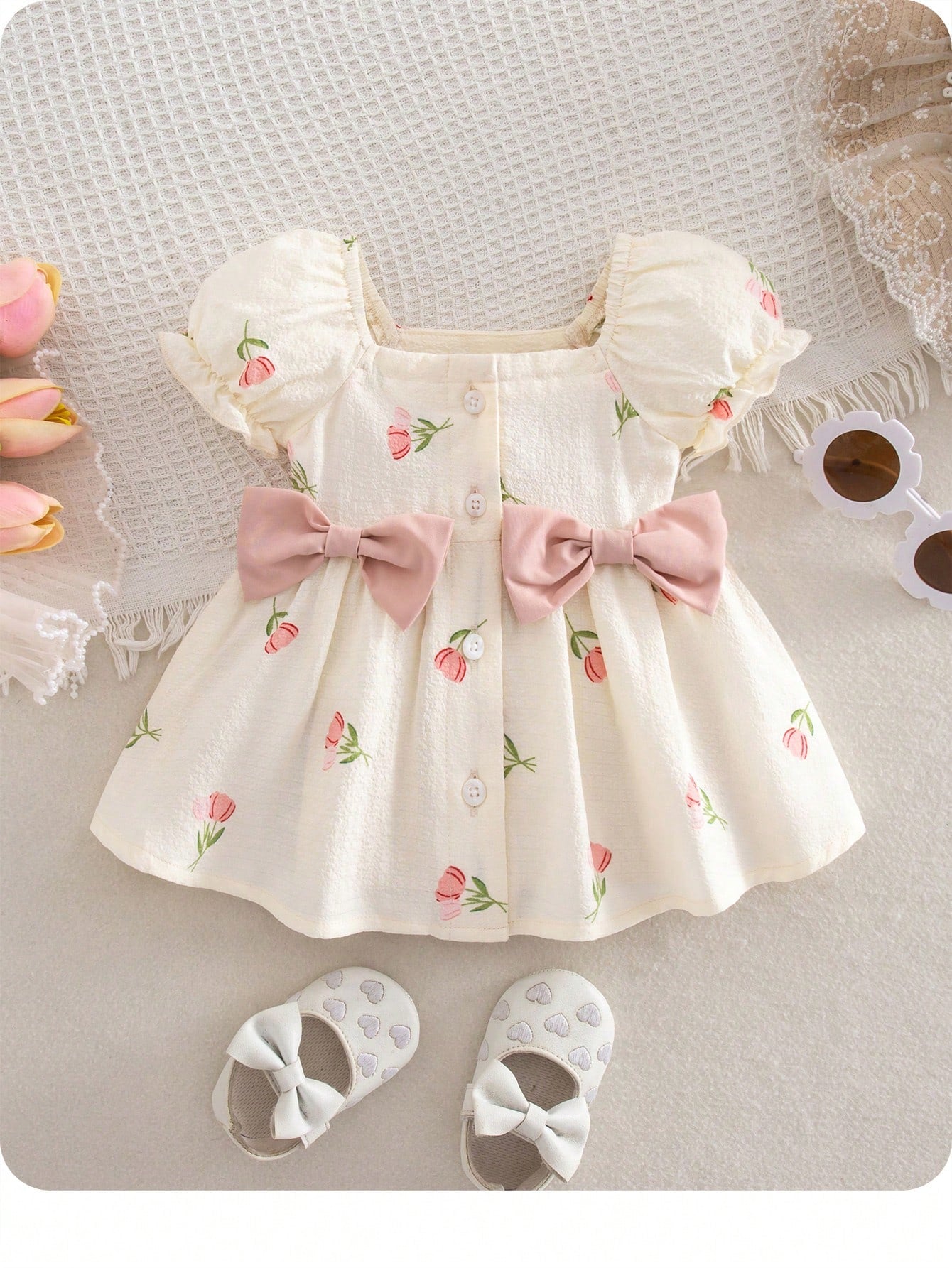 Prenda crema vestido para bebe con lazos rosados y flores vista frontal