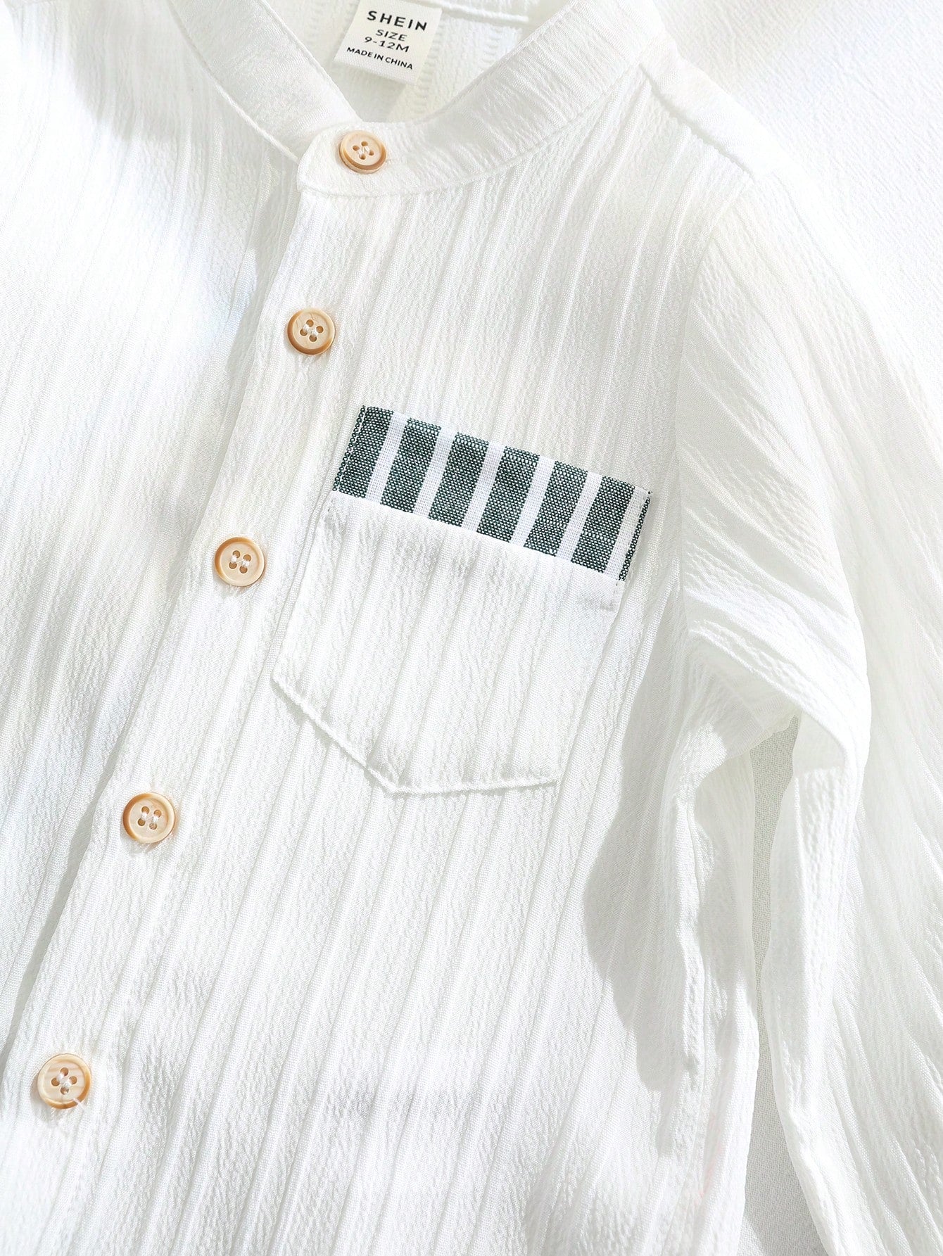 Prenda blanca conjunto para bebe con detalle de botones y bolsillo a rayas