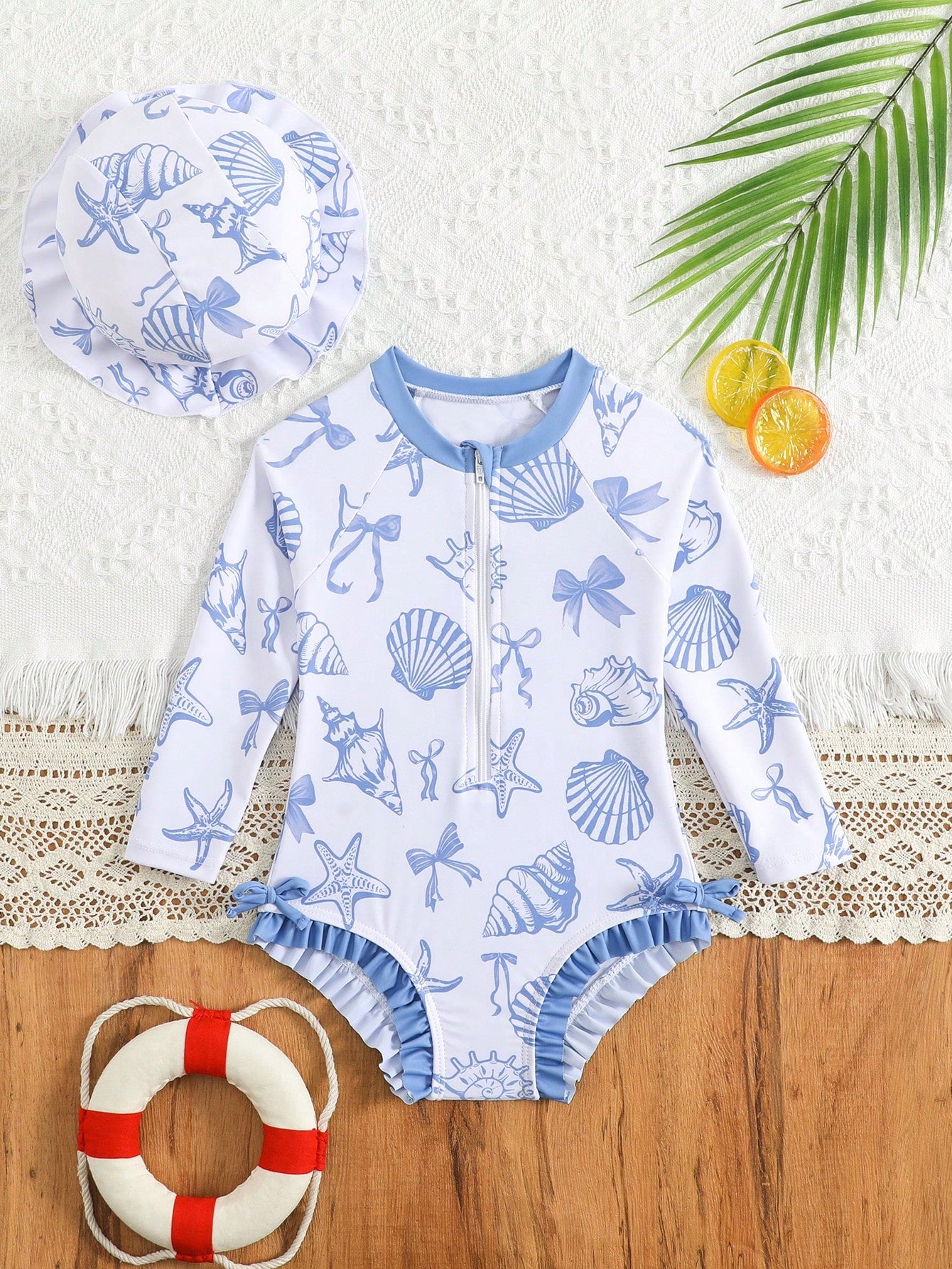 Prenda azul traje de baño para bebe con conchas marinas y gorro vista frontal