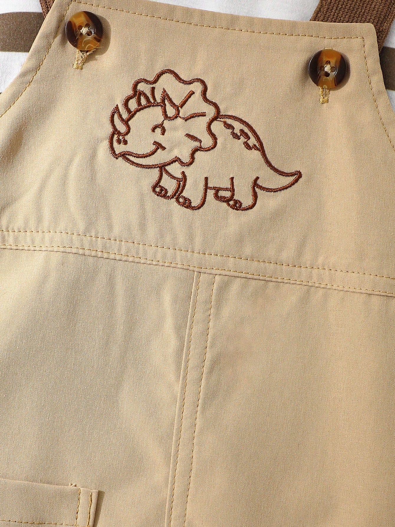 Prenda beige conjunto con overol para bebe y detalle de dinosaurio bordado
