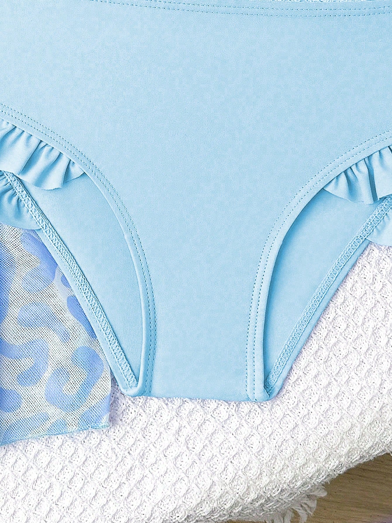 Prenda azul traje de baño para bebe con detalle de braguita con volantes laterales