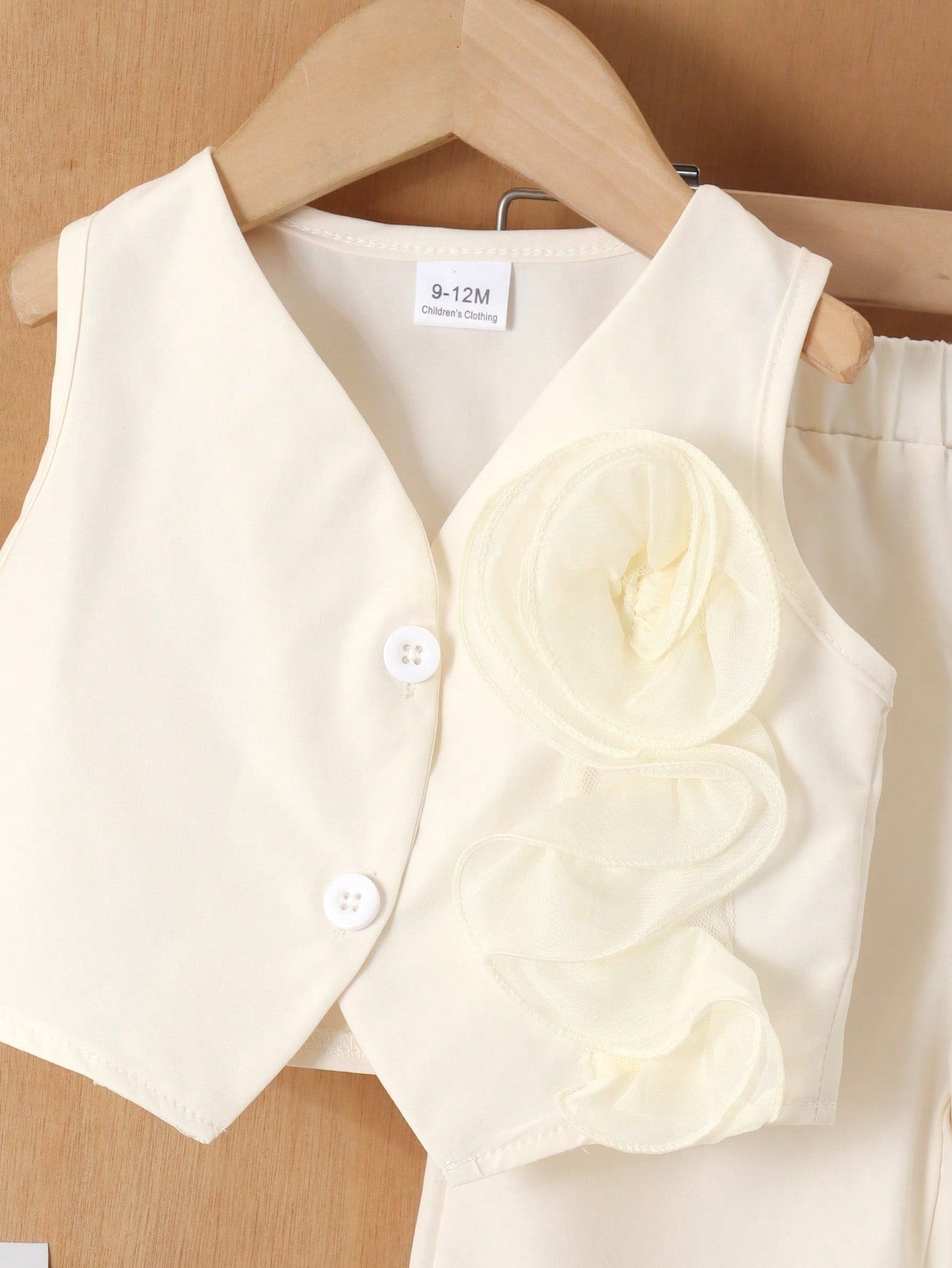 Prenda marfil conjunto para bebe con detalle de flor y botones frontales