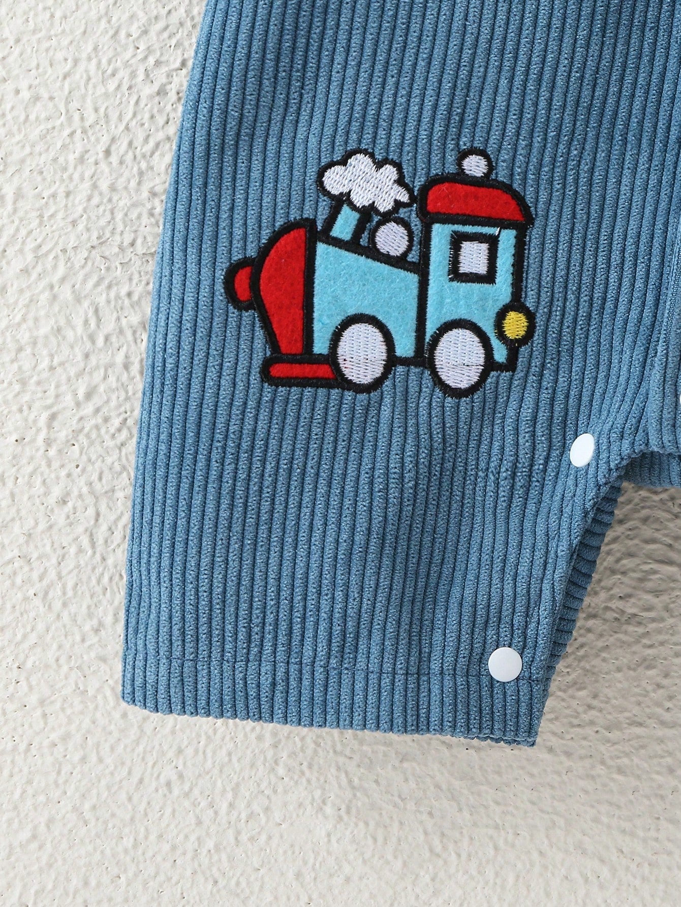 Prenda azul mameluco para bebe con estampado de tren detalle inferior