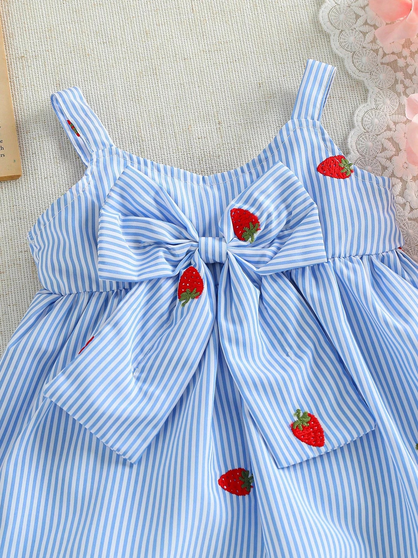 Prenda celeste vestido para bebe con detalle de lazo delantero y bordado de fresa