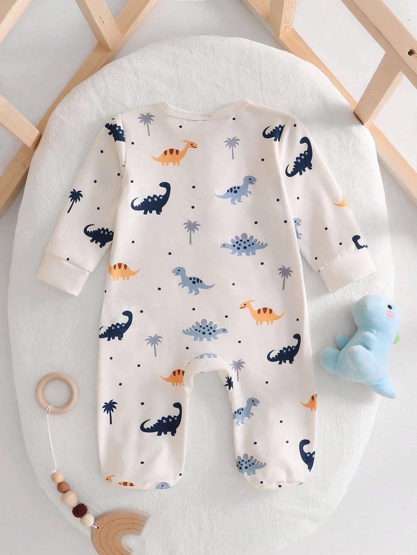 Prenda crema pelele para bebe con estampado de dinosaurios vista posterior
