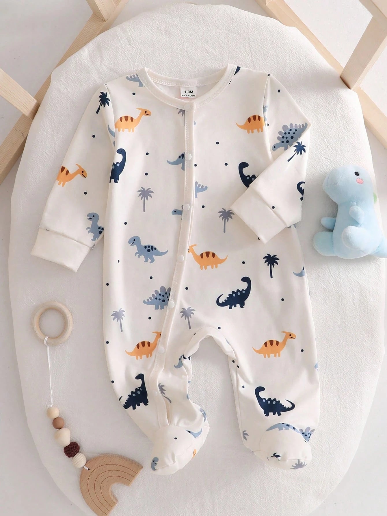 Prenda crema pelele para bebe con estampado de dinosaurios vista frontal
