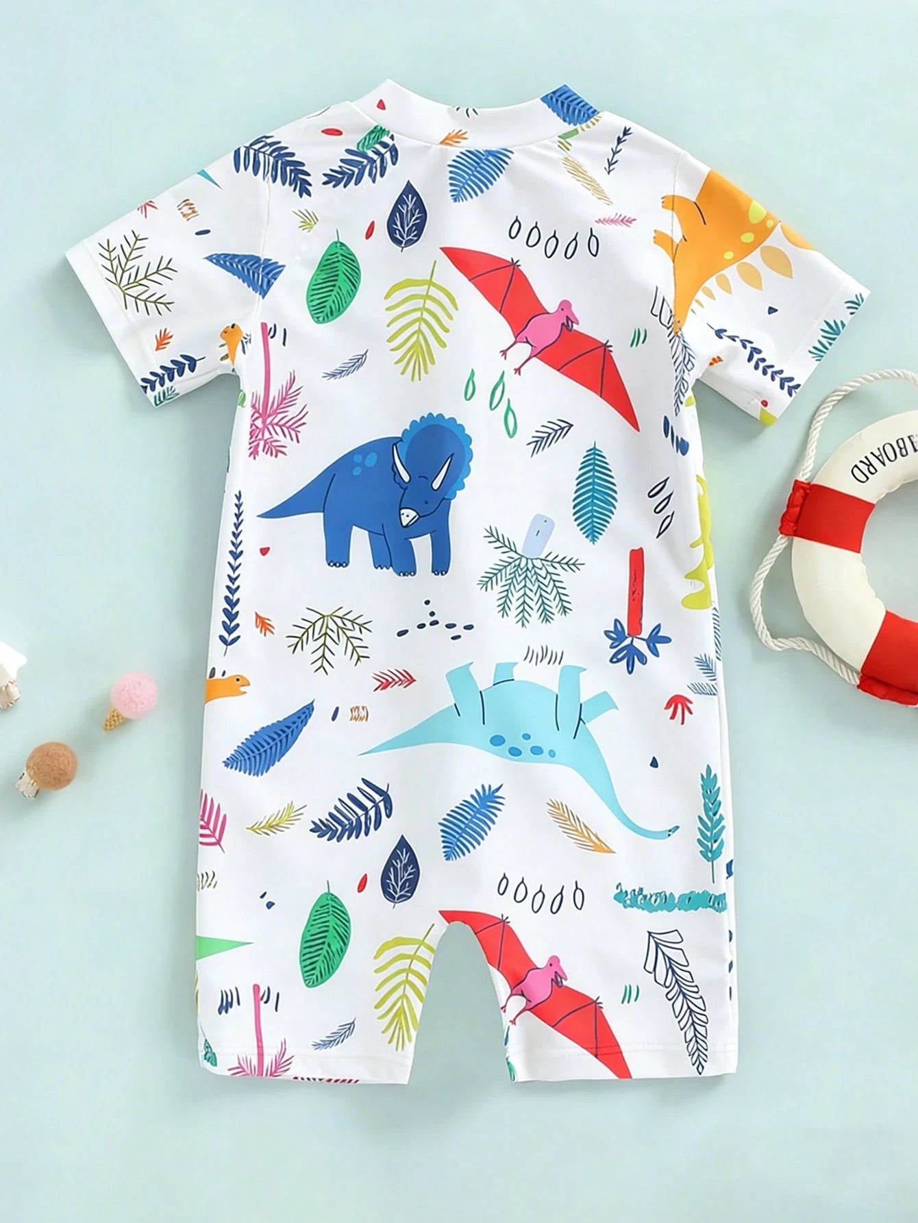 Prenda blanca traje de baño para bebe con estampado de dinosaurios vista trasera